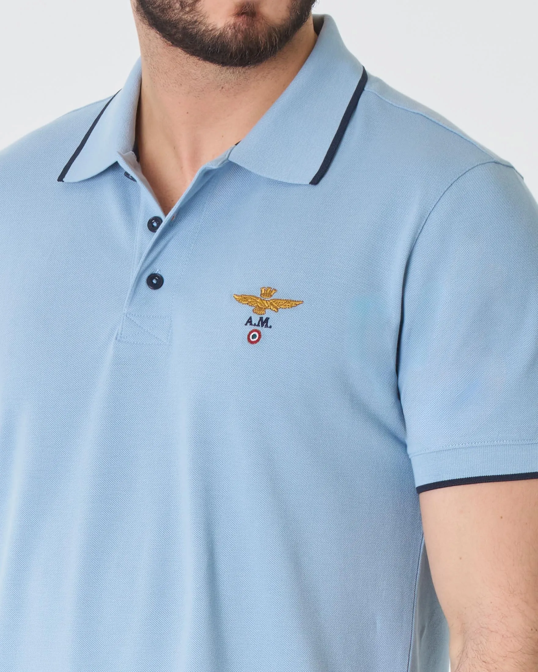 Polo azzurra in piqué di puro cotone con bordino blu e logo ricamato al petto